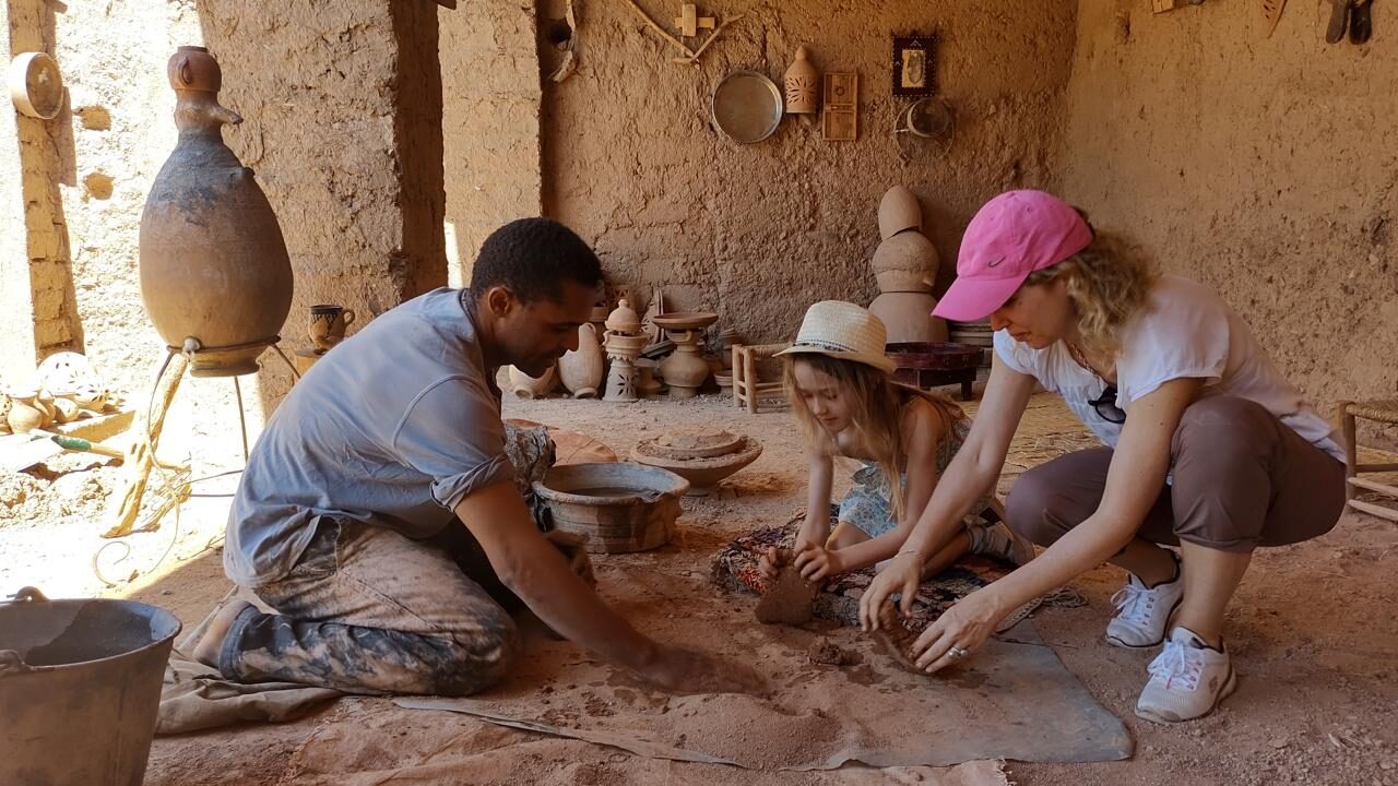 Familie leert pottenbakken bij een lokale ambachtsman in Skoura, Marokko