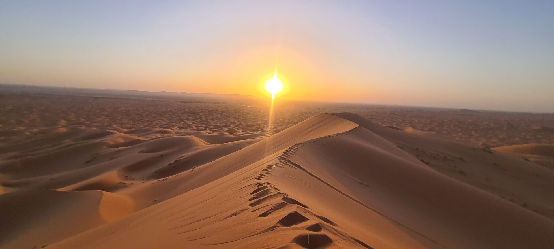 Zonsondergang boven de zandduinen van de Sahara in Marokko