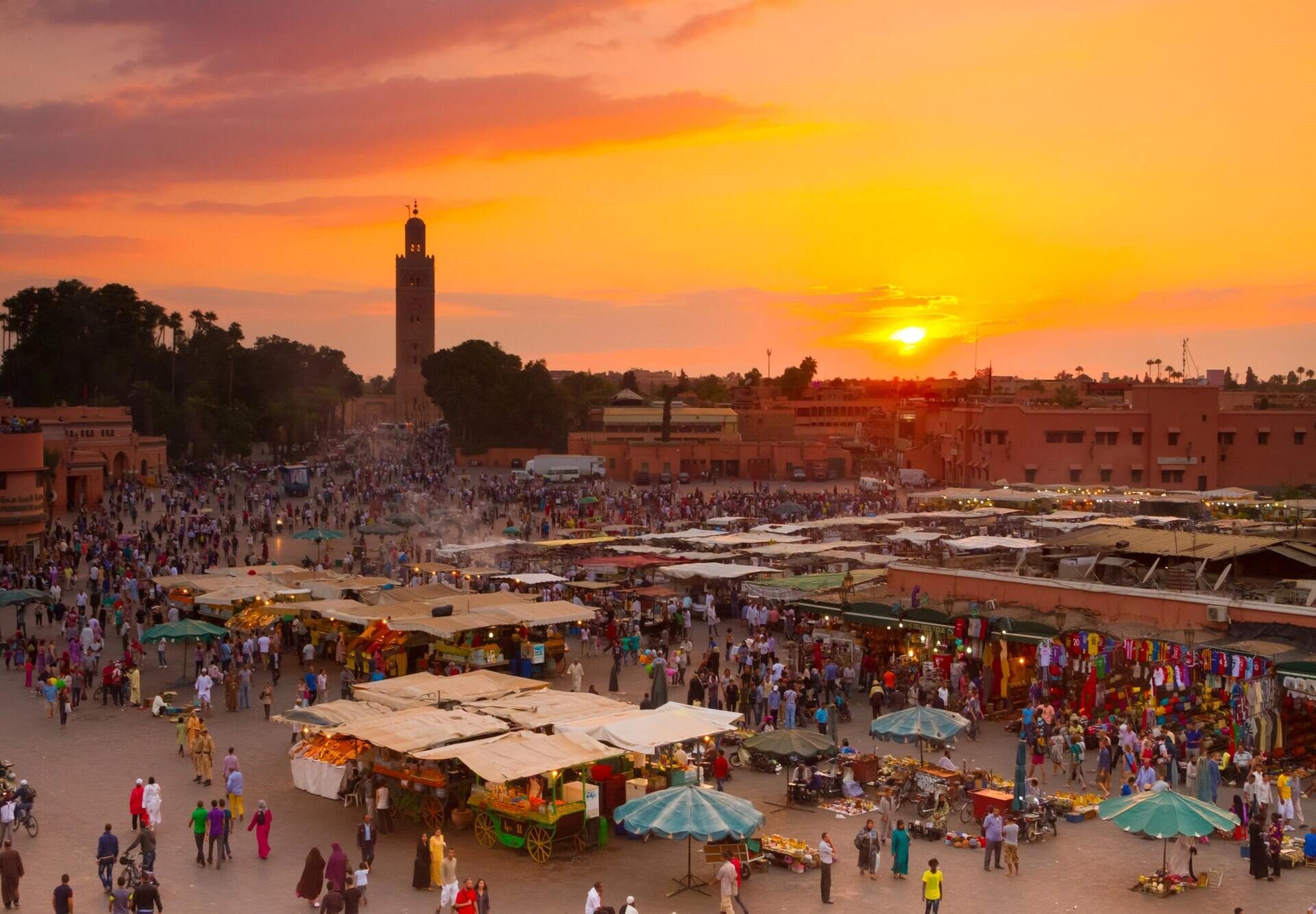 Djemaa el Fna plein in Marrakech bij zonsondergang met marktkramen en de Koutoubia-moskee