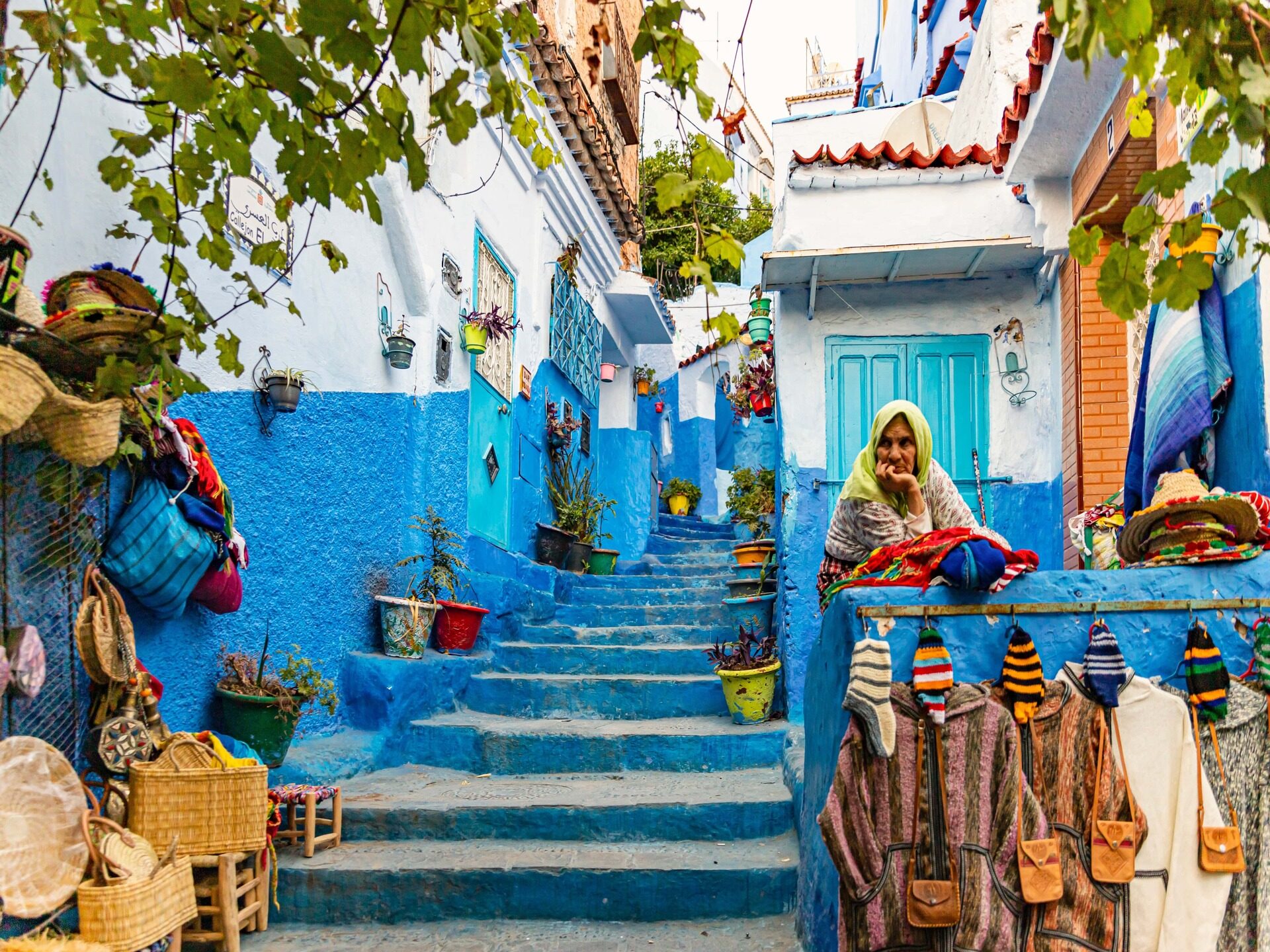Blauwe straat met trappen en lokale vrouw in Chefchaouen, Marokko