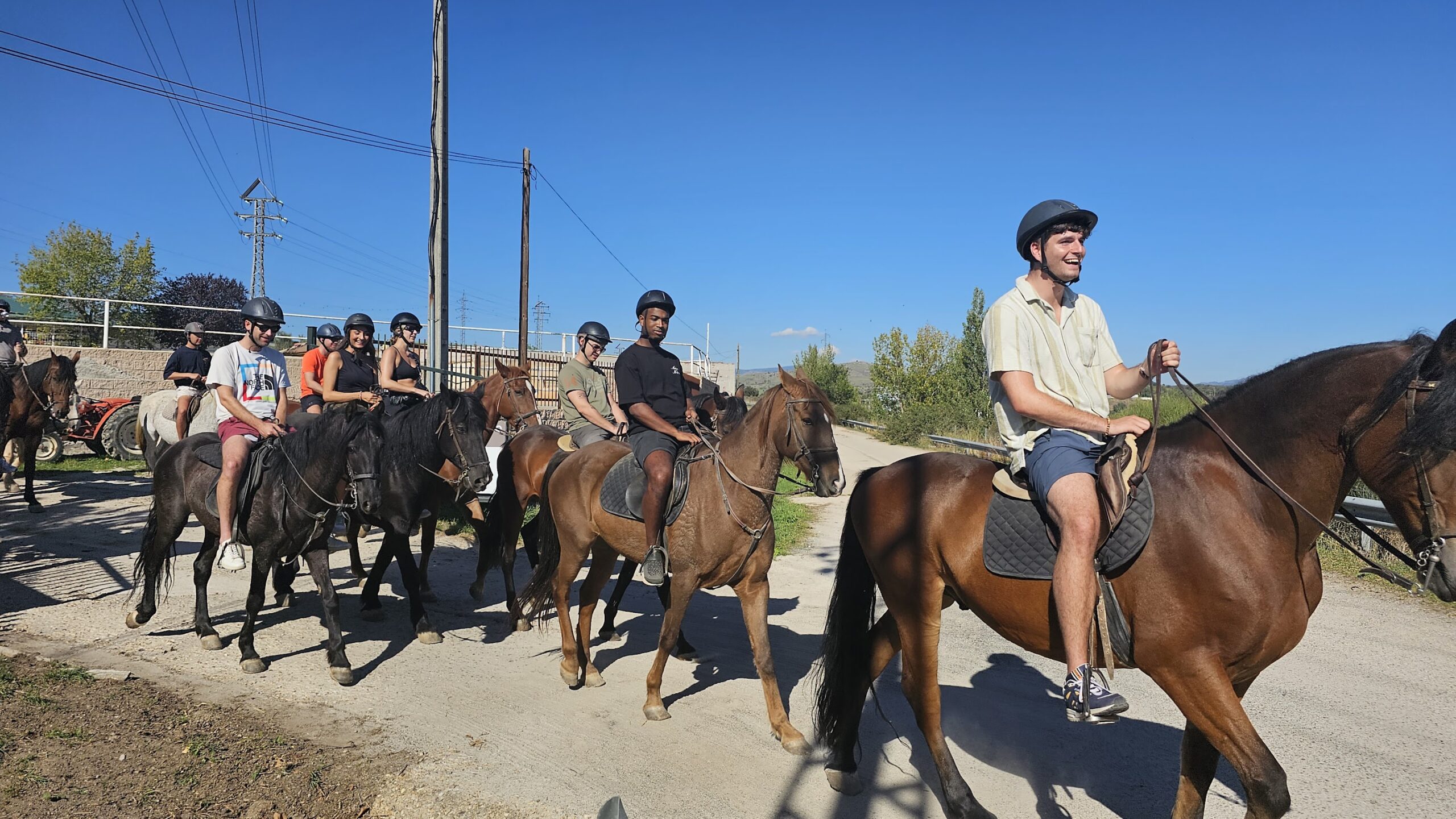 Groep jongeren te paard op een onverharde weg tijdens een begeleide paardrijtocht in een landelijke omgeving.