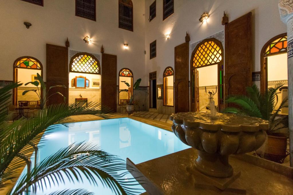 Traditionele Marokkaanse riad met zwembad en fontein in de binnenplaats, sfeervol verlicht voor een authentiek verblijf in Marokko.