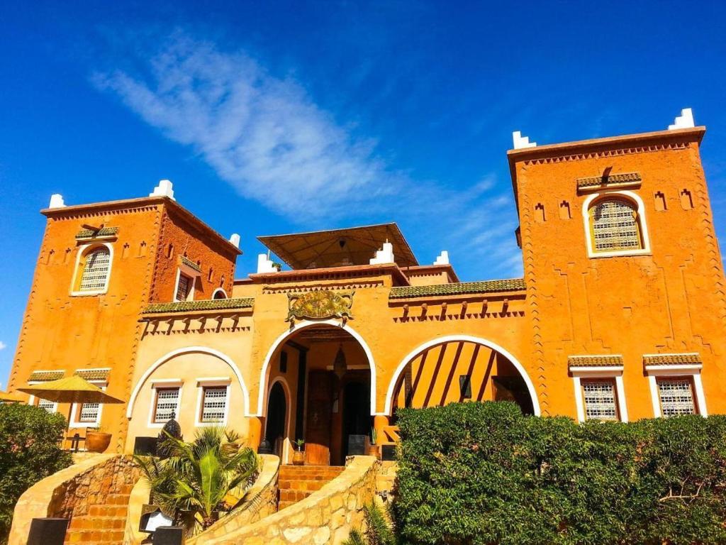 Imposante oranje luxe kasbah Marokko met twee torens witte ornamenten boogvormige ingang trappen en stralend blauwe lucht