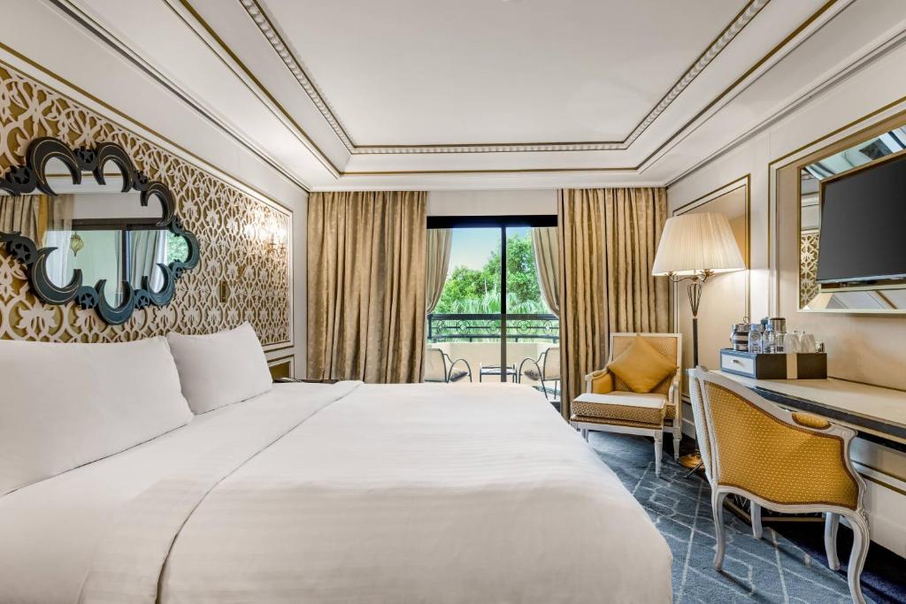Elegante kamer super luxe hotel Fès Marokko met kingsize bed Marokkaans wanddecor gele stoelen en balkon met tuinuitzicht