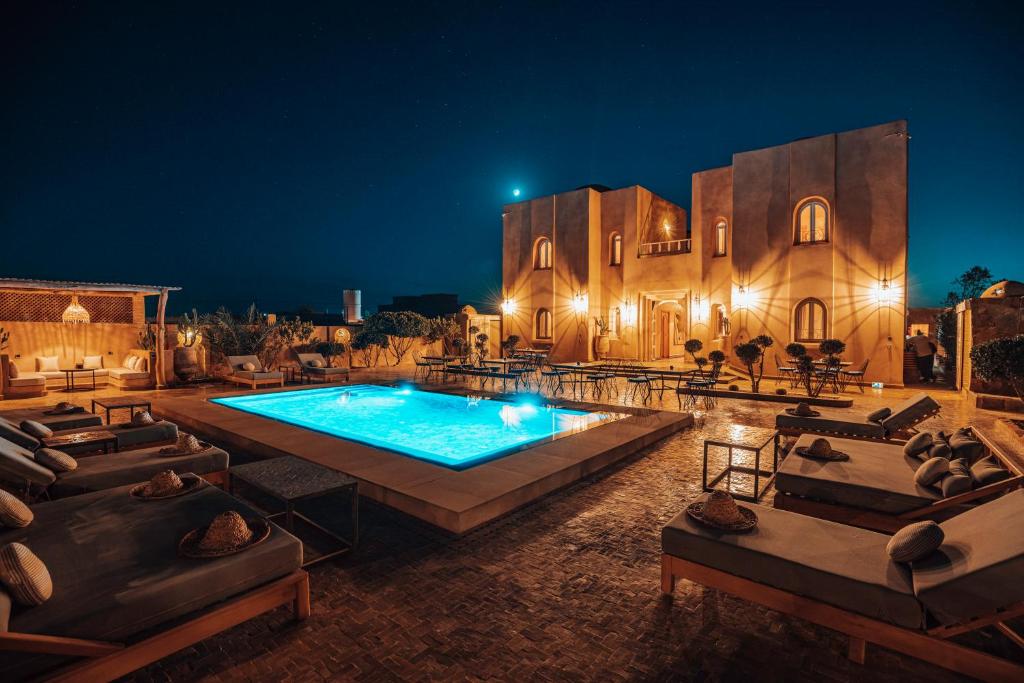 Super luxe woestijnresort Marokko bij nacht met verlicht zwembad ligstoelen Marokkaans gebouw en sterrenhemel