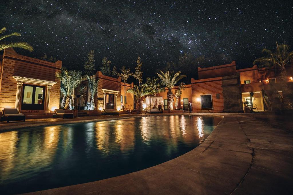 Super luxe kasbah resort Marokko bij nacht met zwembad weerspiegeling palmbomen terracotta gebouwen en melkweg