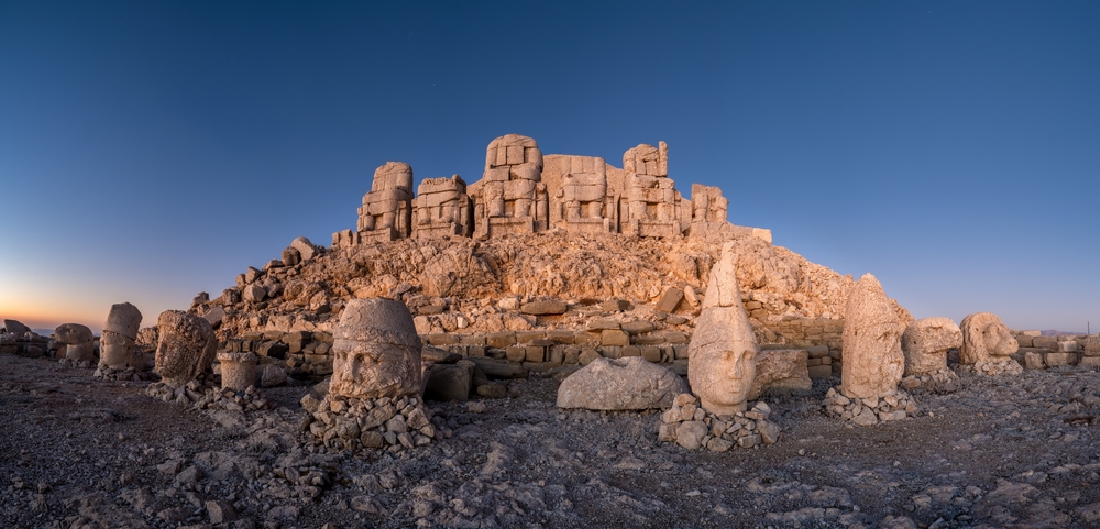 Terras op de Nemrut Dağı met een rij stenen godenhoofden voor de tumulus in laag licht