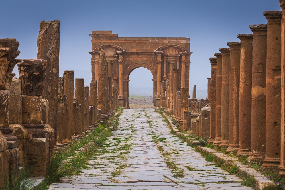 Boog van Trajanus aan het einde van de zuilenstraat in Timgad met geplaveide decumanus
